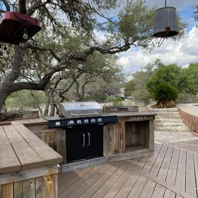 Outdoor kitchen barbecue area made of rustic cedar counters with a stainless steel grill.